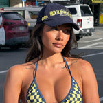 Model wearing a checkered bikini in Navy and Yellow and 'ROGUESEASON' branded cap on a street background