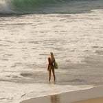 Model standing on a beach with waves in the background