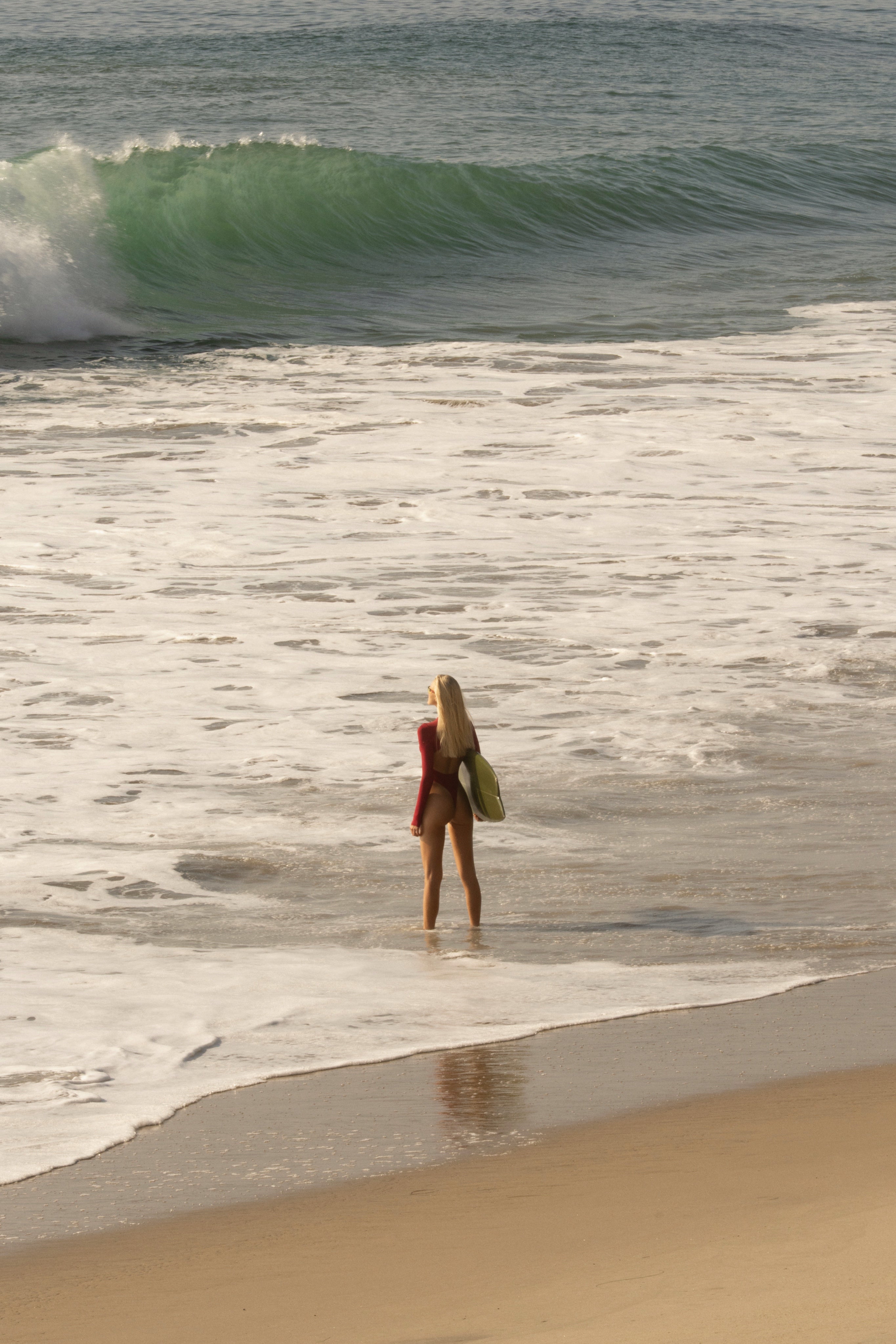 Model standing on a beach with waves in the background