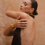 Side cropped in shot of model wearing brown maxi halter neck dress.