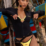 Model wearing yellow and black contrast Rogue Season bikini bottoms with a Black Long Sleeve Swim Shirt at the beach with a vintage radio headset attached to a waist belt.