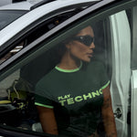 Model wearing a green 'Play Techno' t-shirt sitting in a car.