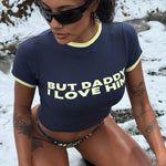 Model wearing a navy Rogue Season cropped t-shirt with printed text and navy and yellow checkered bikini bottoms, outdoors in a snowy environment.