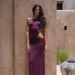 Model wearing a burgundy swimsuit and matching sheer maxi skirt near a textured wall