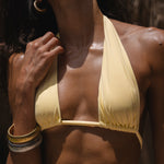 Model wearing a yellow bikini top with a blurred background