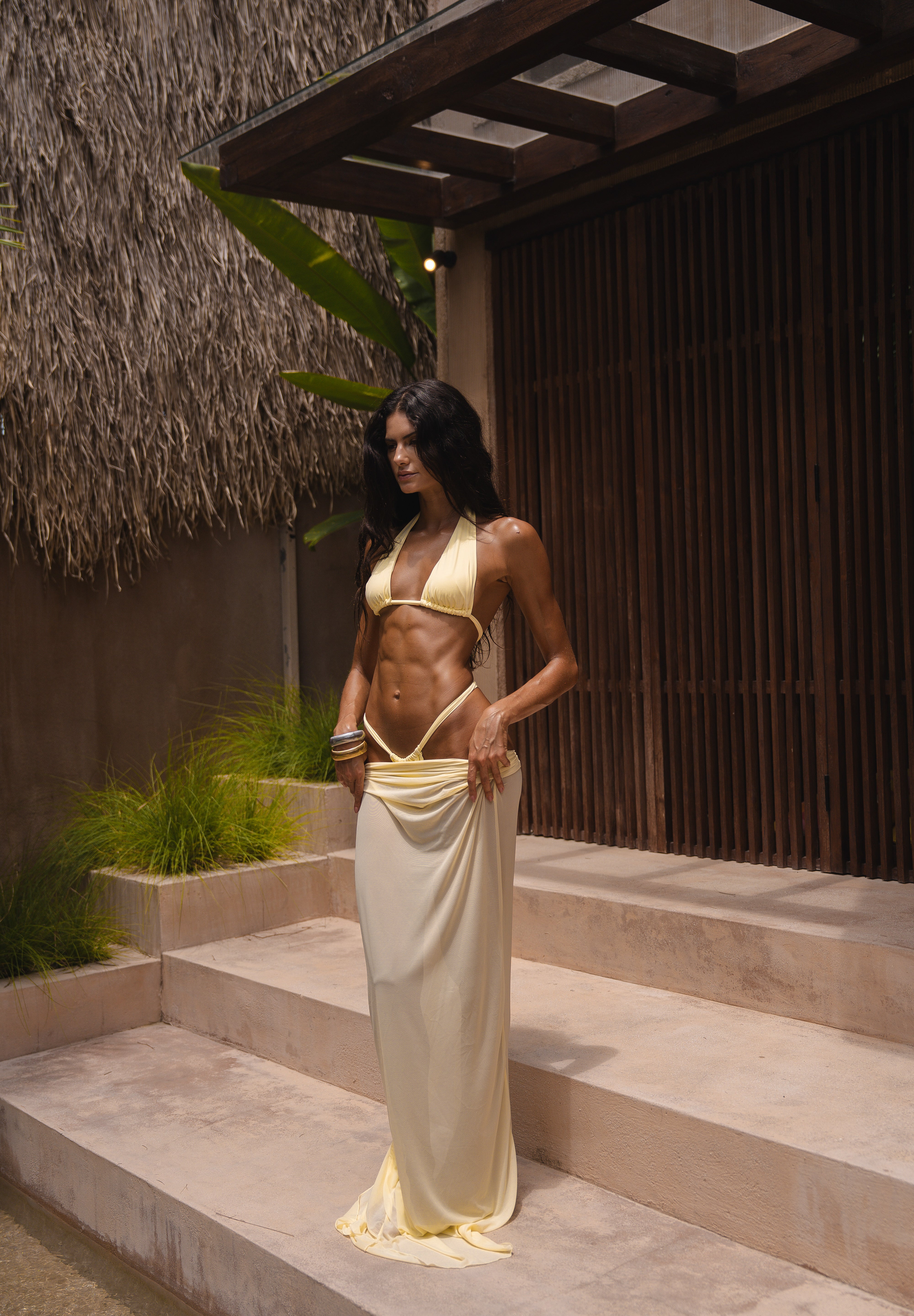 Model wearing a yellow bikini top and bottoms with a sheer maxi skirt in yellow