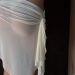 White sheer fabric draped over a model against a dark background