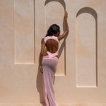 Back shot of model wearing a soft pink one-piece swimsuit with a sheer maxi skirt.