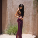 Model wearing a burgundy swimsuit and matching sheer maxi skirt near pool with a textured wall