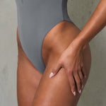 Close up detailing of  grey one piece swimsuit fabric worn on model.