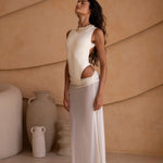 Model wearing an ivory bodysuit with a matching sheer maxi skirt with a fitted silhouette, standing indoors against a neutral-toned wall with minimal decor.