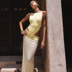 Model wearing a yellow swimsuit and matching sheer maxi skirt near a textured wall