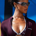 Close up model shot wearing a short-sleeve burgundy swim shirt with matching bikini bottoms, standing in front of a blue and black striped background.