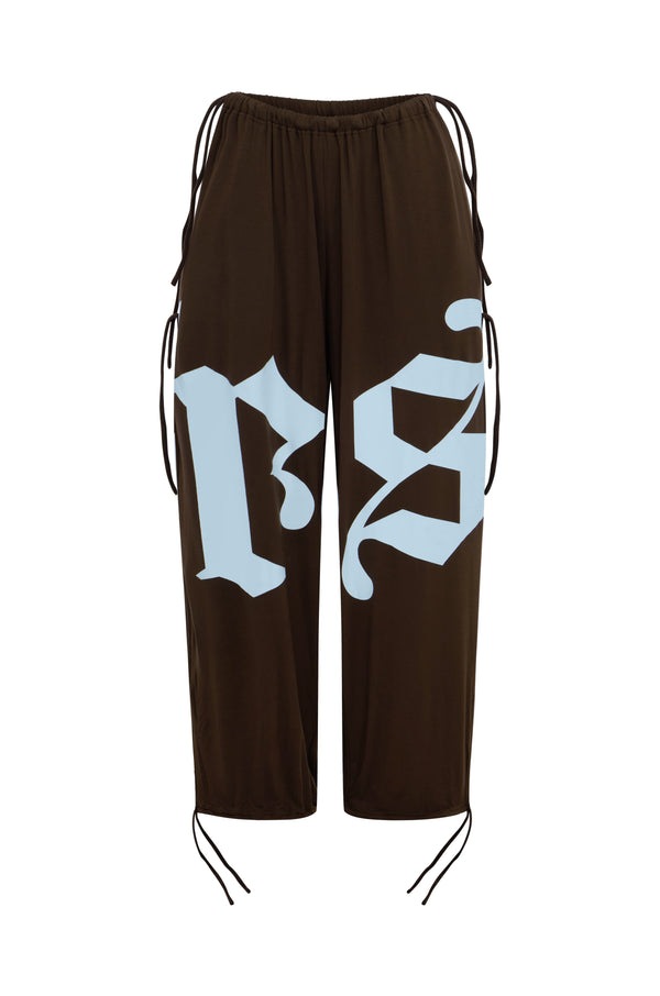 Dark brown balloon pants featuring a large light blue gothic-style 'rs' graphic on the front, with brown drawstrings at the sides and hems, shown against a plain white background.